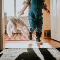 Little girl with a toy bunny rabbit in a sunny bedroom