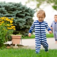 Fraternal Twins play in the summer on grass and concrete