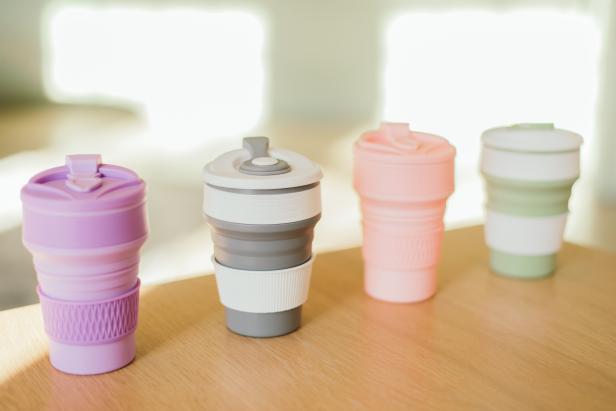 A set of multi-colored folding silicone cups for drinks without plastic in a waste-free style on the background of the interior, close-up. Product photography. Store content.