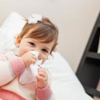 Little girl wiping her nose with a tissue