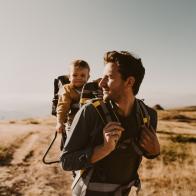 Photo of young father spending time with his son by taking him on a hike while he is in a baby carrier backpack