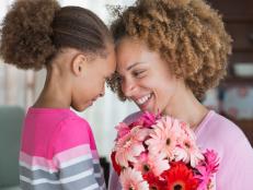Black mother and daughter holding bouquet of flowers