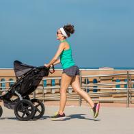 Fit mother jogging on a boardwalk with baby stoller.