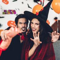 Couple having fun wearing dressed carnival halloween costumes and makeup posing with bats and balloons on background at the halloween party.Halloween holiday celebration concept