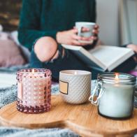 Cropped shot of an unrecognizable young woman relaxing with a book and a cup of coffee on her bed at home