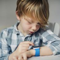 Young boy concentrating using a smart watch sat at a table