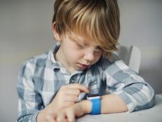 Young boy concentrating using a smart watch sat at a table