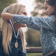 Daughter giving a mother a gold medal in public park