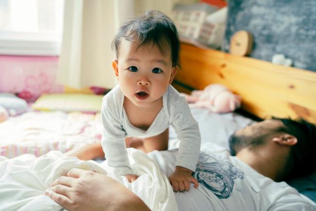 Morning Mood Asian baby wake up early before daddy and playful on the bed
