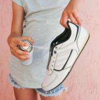 Female hand holding a spray deodorant for shoes.