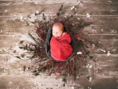 A portrait of a newborn baby wrapped in Christmas themed cheesecloth and crochet wrap.