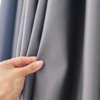 close-up of a woman's hand touching the curtain, gray blackout fabric, light-blocking fabric