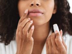Lip Care. Unrecognizable black woman applying moisturising chapstick on lips, cropped image, closeup