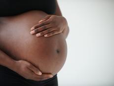 Midsection of pregnant Black woman holding belly