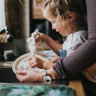 Cute little girl helping a grown up do the dishes.