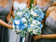 High angle view of bride and bridesmaids holding blue and white flower bouquets.