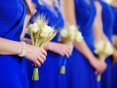 Row of bridesmaids wearing blue dresses holding wedding bouquets at wedding ceremony