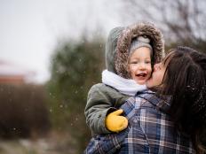 Mother and child daughter enjoying snowfall, happy family.