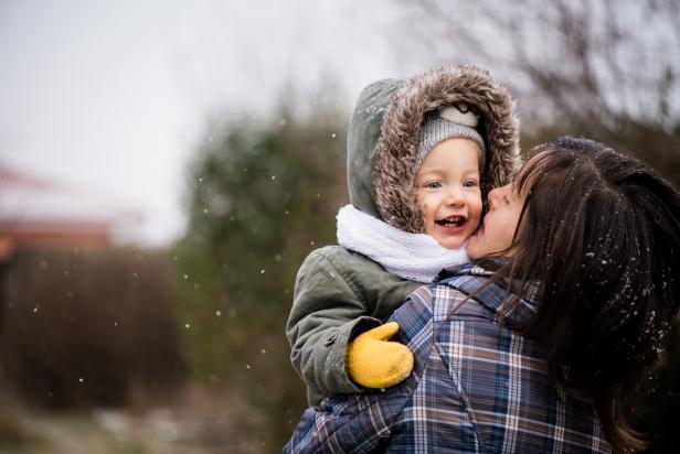 Mother and child daughter enjoying snowfall, happy family.