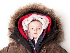Concept portrait of a cute 3 month baby girl in many winter jackets.