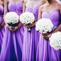 Wedding ceremony with bridesmaids wearing purple dresses and holding white flowers.