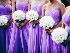 Wedding ceremony with bridesmaids wearing purple dresses and holding white flowers.