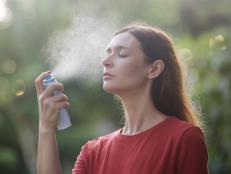 Woman spraying facial mist on her face, summertime skincare concept