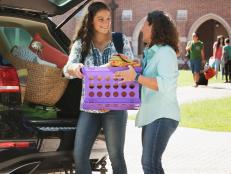 Mother helping daughter unload car at college dormitory