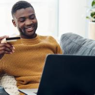 Shot of a young man using a laptop and credit card at home