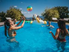 Group of young friends playing with beach ball on swimming pool