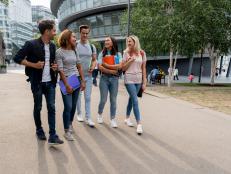 Diverse group of students walking on the street talking and holding notebooks - lifestyle concepts