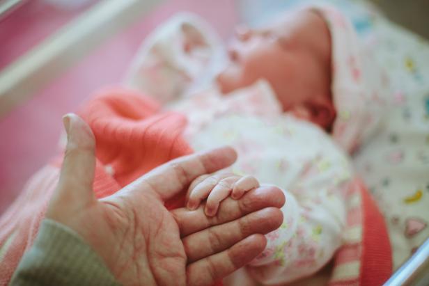 Newborn baby holding on to Mothers hand while in hospital a few hours after being born.