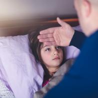 father checking daughter's forehead for fever