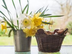 Beautiful bouquet of white and yellow daffodils and wicker basket with hun eggs against the window. Easter holiday concept