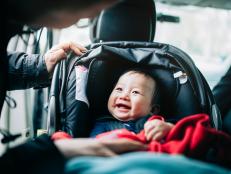 Close up of mother taking care of cute smiling baby on car seat in car