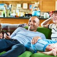 Happy family reclining on green sofa and watching TV