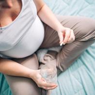 Young pregnant woman holding pills in hand