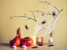 Home made Halloween decorations with branch, spiders, web, candles and pumpkins. Vintage toning. Idea for interior design.