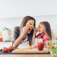 Mother and daughter having fun with the vegetables in the kitchen.