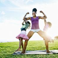 Woman lifting children with biceps in park