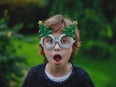 A blonde boy with funny expression with Christmas glasses.