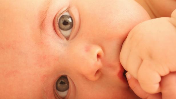 3-4 month old baby boy laying.Bebé de  3-4 meses con las manos en la boca.