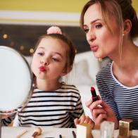 Mother and daughter applying make up together, using lipstick