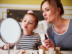 Mother and daughter applying make up together, using lipstick