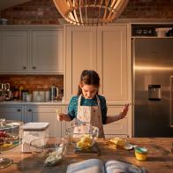 Girl weighing butter and ingredients for baking a cake