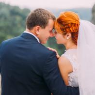 Wedding couple softly embracing at rocky mountains against the sky. Cute romantic moment. Back view.