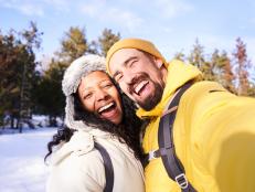 Happy and beautiful interracial young marriage taking a smily selfie in the snow.