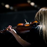Beautiful girl playing the violin in concert hall
