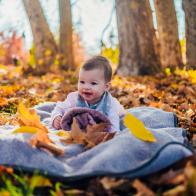 Cute baby girl on blanket at park on sunny autumn day