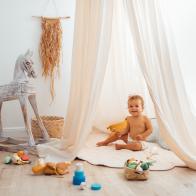 Children's playroom full of toys. Beautiful decoration nursery with natural macrame decoration, organic canopy, wicker baskets and wood toys. Zero waste and ecological concept.